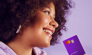 Mulher de perfil segurando um cartão roxinho do Nubank